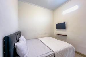 a small bedroom with a bed and a flat screen tv at JJ House Mitra RedDoorz in Jakarta