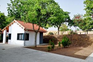 a small white house with a tree in front at GlampINN Fuente Obejuna in Fuente Obejuna