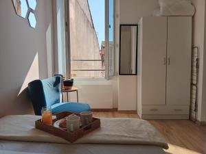 a room with a bed and a blue chair with a tray of food at Les Apparts de Marmande - Petit Cocon en ville in Marmande