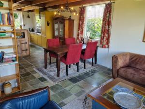 a living room with a wooden table and red chairs at The Barn in Loosdrecht