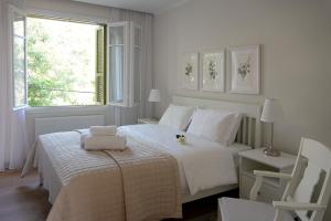 a white bedroom with a bed and a window at Stou Savvide - Pera Pedi Stone Manor in Perapedhi