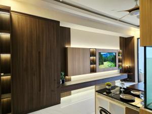 Il comprend une cuisine avec des placards en bois et une télévision murale. dans l'établissement Apartemen SkyHouse BSD, à Samporo