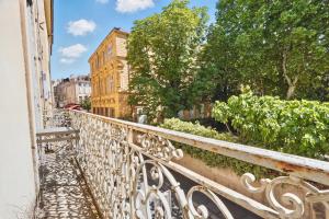 a white railing on a balcony with trees and buildings at Le jardin de Ponteves in Aix-en-Provence