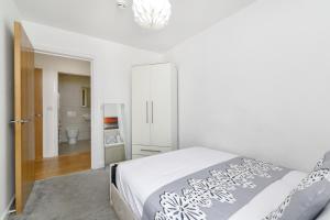 a white bedroom with a bed and a bathroom at 2 Bedroom Apartment near City Airport in London