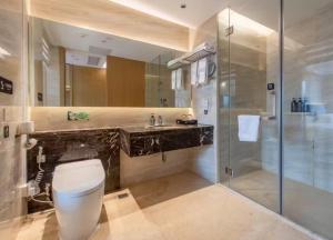 a bathroom with a toilet and a glass shower at Mido International Hotel in Guangzhou