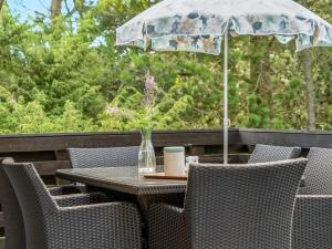 an outdoor table with chairs and an umbrella at Holiday Home Alfi - 150m from the sea by Interhome in Sæby