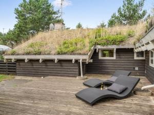 a deck with a bench and a grass roof at Holiday Home Alfi - 150m from the sea by Interhome in Sæby