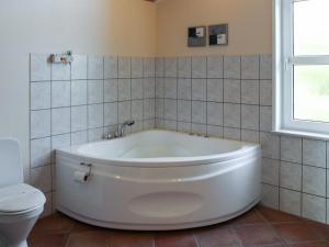 a white tub in a bathroom with a toilet at Holiday Home Calina - 300m from the sea by Interhome in Sæby