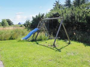 a playground with a blue slide in the grass at Holiday Home Calina - 300m from the sea by Interhome in Sæby +17 photos