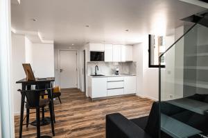 a kitchen with white cabinets and a table in a room at Loft Prestige - Leiria Centro in Leiria