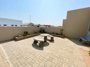 eine Terrasse mit einer Bank und einem Tisch auf einem Gebäude in der Unterkunft Omuhama Ocean Escape in Mondesa