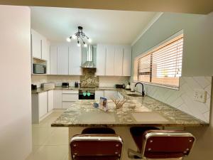 eine Küche mit weißen Schränken und einer Marmoroberfläche in der Unterkunft Omuhama Ocean Escape in Mondesa