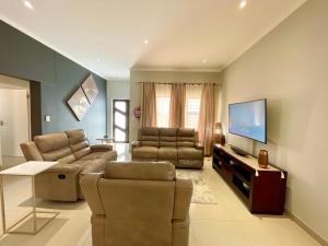 ein Wohnzimmer mit zwei Sofas und einem Flachbildfernseher in der Unterkunft Omuhama Ocean Escape in Mondesa