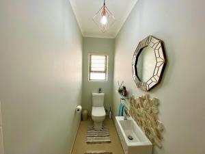 ein Badezimmer mit Toilette, Waschbecken und Spiegel in der Unterkunft Omuhama Ocean Escape in Mondesa + 9 Fotos