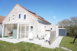 Casa blanca con patio con mesa y sillas en Kustverhuur, Vakantiepark Fort Soleil 28, en Breskens