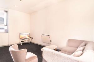a living room with a couch and a tv and chairs at Cosy & Convenient Central Blackburn 2BED Apartment in Blackburn