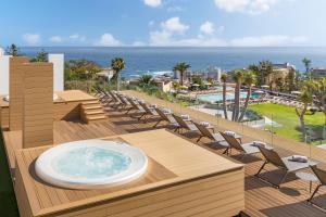a hot tub on a deck with chairs and the ocean at TUI BLUE Atlantic Hills in Puerto de la Cruz