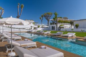 a swimming pool with lounge chairs and umbrellas at TUI BLUE Atlantic Hills in Puerto de la Cruz