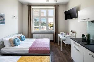 a bedroom with a bed and a desk and a window at Wavelo Apartments in Kraków