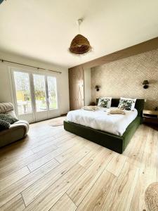 una camera da letto con un letto grande e pavimenti in legno di Ô Refuge de Théo et Vic' a Saint-Martin-du-Vieux-Bellême