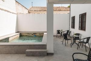 バエサにあるAlojamientos Estrella Baezaの建物内のプール(椅子、テーブル付)