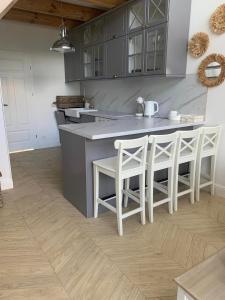 a kitchen with gray cabinets and white stools at NAD JEZIORAMI Niedźwiady in Kolonia Pawłówek