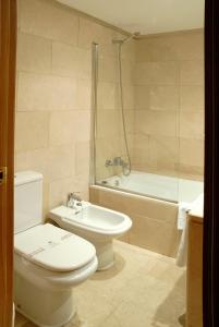 a bathroom with a toilet and a sink and a tub at Reyes Católicos in Seville