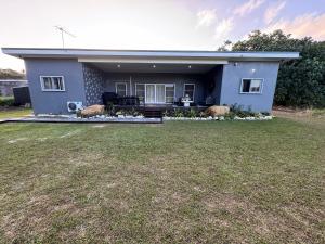 a blue house with a large yard in front of it at Te Kopa Villa in Rarotonga