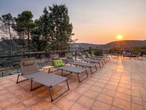 a row of chairs on a patio with the sunset at Casa Clarita hasta 21 personas, piscina a 40 min de Madrid y aeropuerto in Perales de Tajuña