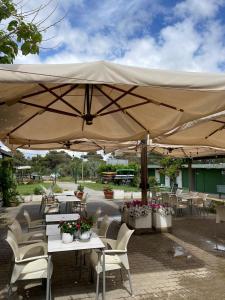 a patio with tables and chairs under a large umbrella at Residence delle Nazioni - Spiaggia privata su richiesta in Principina a Mare