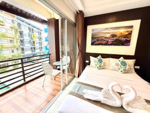 a hotel room with a balcony with two swans on the bed at Thai Classic House in Patong Beach