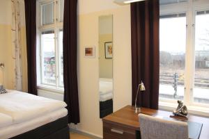 a bedroom with a bed and a desk with a mirror at Hotell Lilla Station in Köping