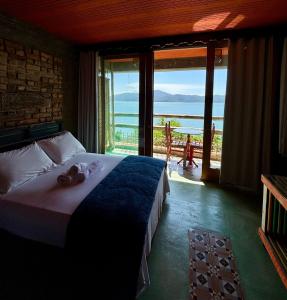 a bedroom with a bed with a view of the ocean at Tainha da Praia Aparthotel in Bombinhas