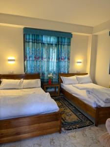 a bedroom with two beds and a window at Mountain Whisper Homestay Yuksom in Pemayangtse +9 photos