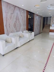 two white couches in a room with a marble wall at نزل حياة طيبة للنزل السياحة in Al Nawārīyah
