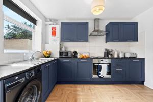 a kitchen with blue cabinets and a washing machine at NEW! Spacious 4 bedroom 4BR with Private Parking near city Centre in Leamington Spa