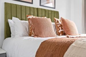 a bed with brown and white pillows on it at NEW! Spacious 4 bedroom 4BR with Private Parking near city Centre in Leamington Spa +18 photos