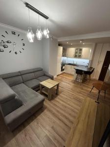 a living room with a couch and a clock on the wall at Apartament Wygodny 2 in Białystok