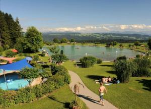 a group of people in a park with a lake at Ferienwohnung Allgäu-Harmonie - Pool, Sauna, Bergblick, 2 Zimmer in Scheidegg
