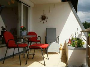 a patio with red chairs and a table on a balcony at Ferienwohnung Allgäu-Harmonie - Pool, Sauna, Bergblick, 2 Zimmer in Scheidegg