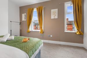 a bedroom with a bed and two windows with yellow curtains at Luxury, Comfy Home in Manchester Center in Manchester