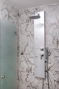 y baño con ducha y papel pintado con motivos florales. en Domus Chiara al Colosseo, en Roma