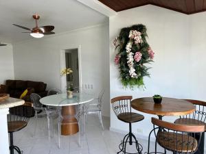 a living room with a table and chairs and flowers on the wall at Flat Golden Beach in Guarujá