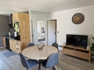 a living room with a table and chairs and a television at Maison cosy et nature avec vue sur le lac de Neuvic in Liginiac