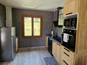 a kitchen with a stainless steel refrigerator and a microwave at Maison cosy et nature avec vue sur le lac de Neuvic in Liginiac