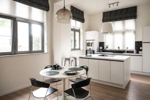 a kitchen with white cabinets and a table and chairs at Quiet and cosy apartment near the city center of Diest in Diest