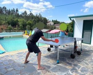 un uomo che gioca a ping pong su un tavolo da ping pong di Casa Agostinho - with private pool near Coimbra a Graça