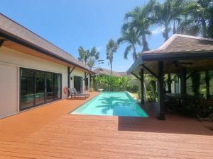 a house with a swimming pool on a wooden deck at Tara13-Oriental Villa 3BR private pool Layan Beach in Bang Tao Beach