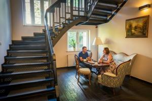 a man and woman sitting at a table under a staircase at Villa Lessing in Polanica-Zdrój