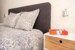 a bed with a gray headboard and a book on a night stand at Quiet and cosy apartment near the city center of Diest in Diest